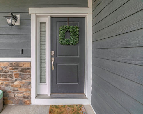 Entrance To A House With Side Light And Gray Front Door Decorated With Wreath