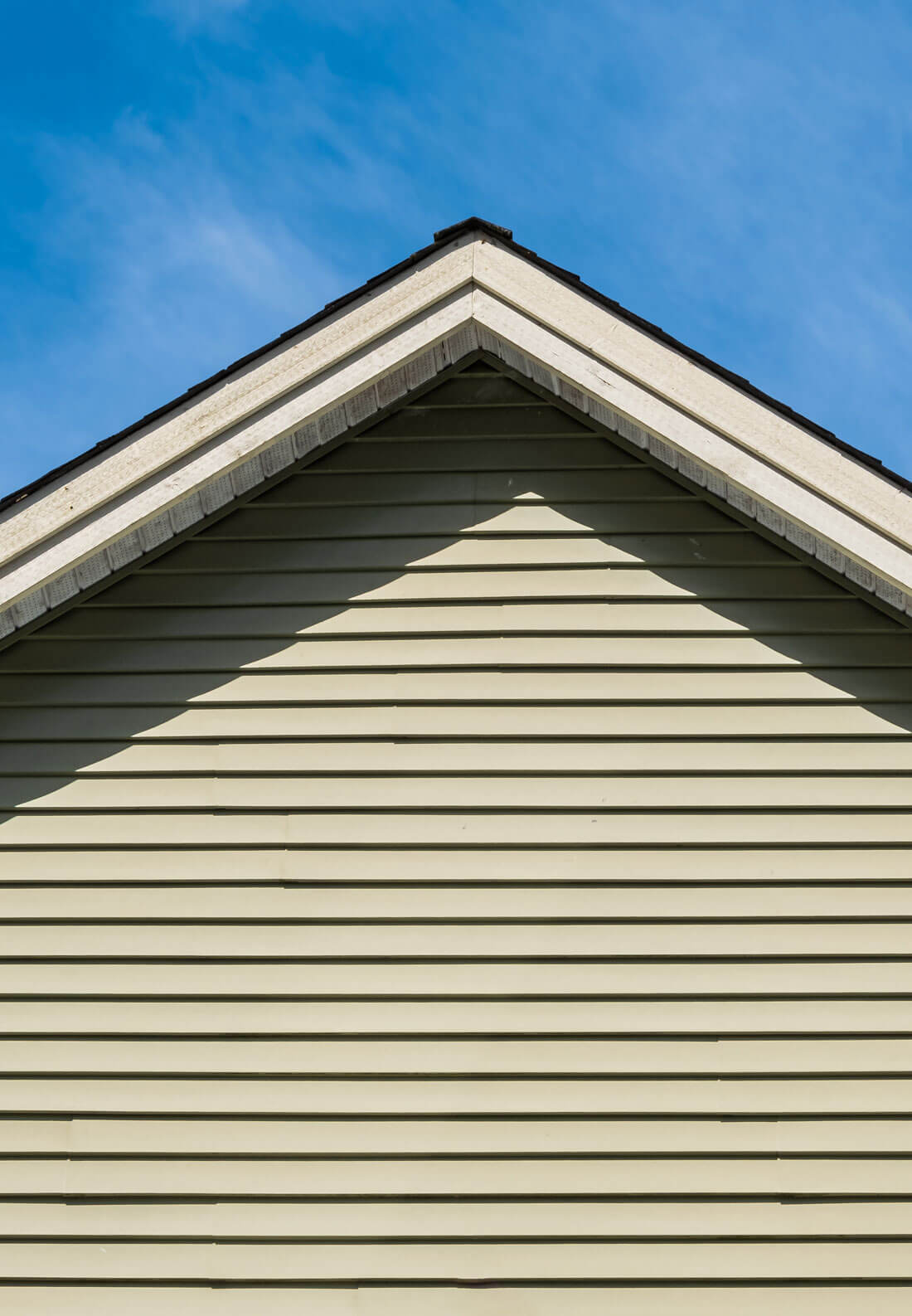 Top Of House. Triangle House Top In The Blue Sky Background. Gray Vinyl Wooden Siding Panel On The House.